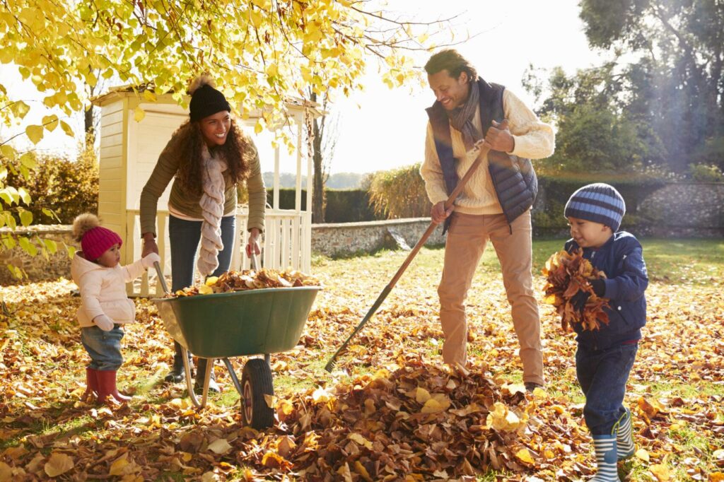 Children,Helping,Parents,To,Collect,Autumn,Leaves,In,Garden