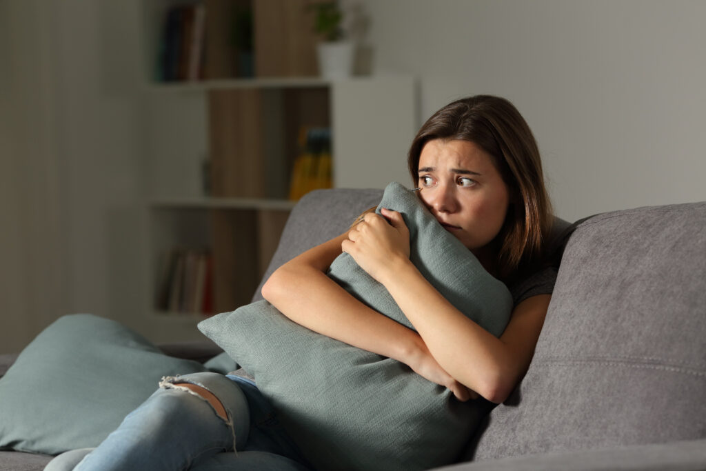 Scared,Teen,At,Home,Embracing,Pillow,Sitting,On,A,Couch